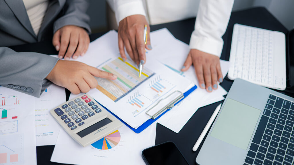 Businesswomen discussing financial report and data analysis with calculator and laptop